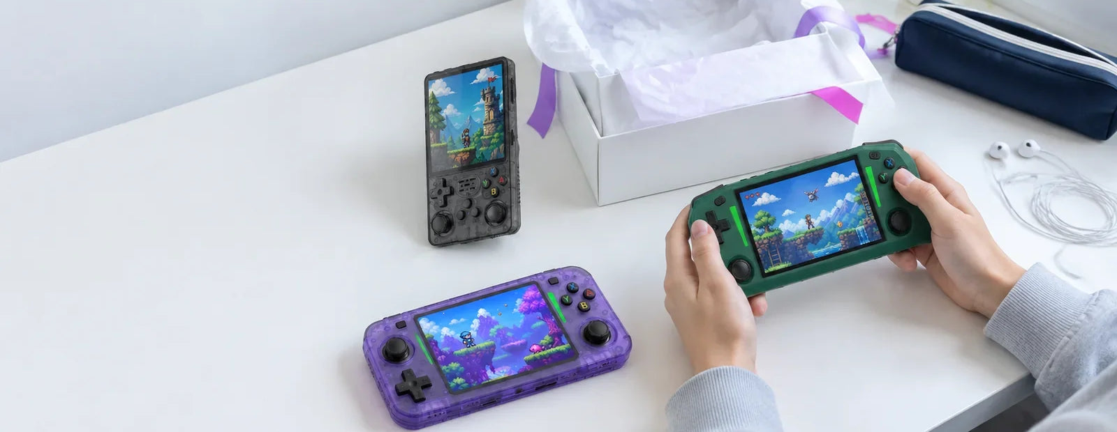 Cadeau ado gamer : trois consoles rétro portables autour d'une boîte cadeau sur un bureau
